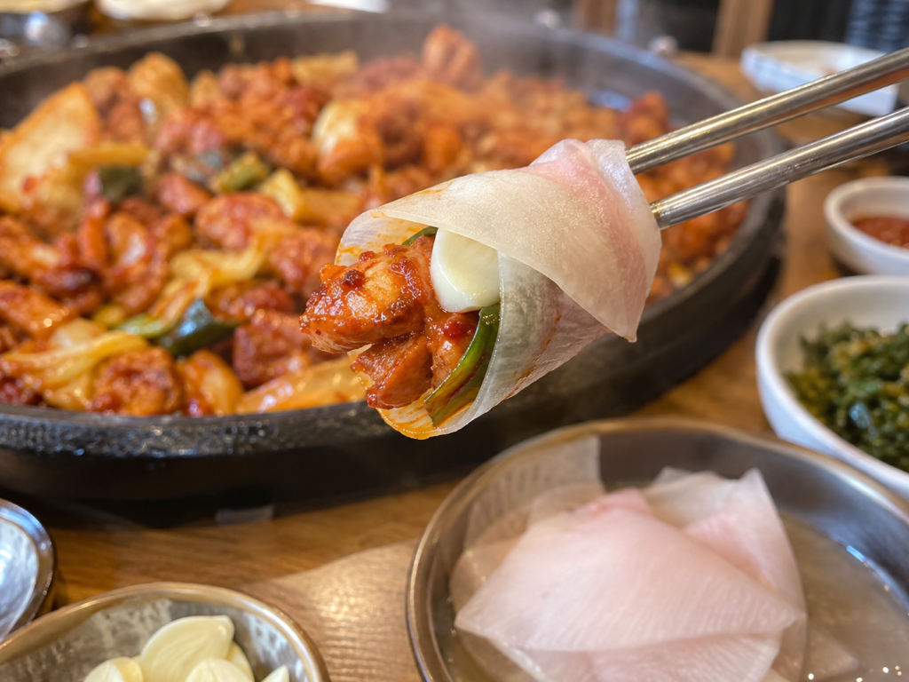 Korean dakgalbi wrapped in thin pickled radish ssammu