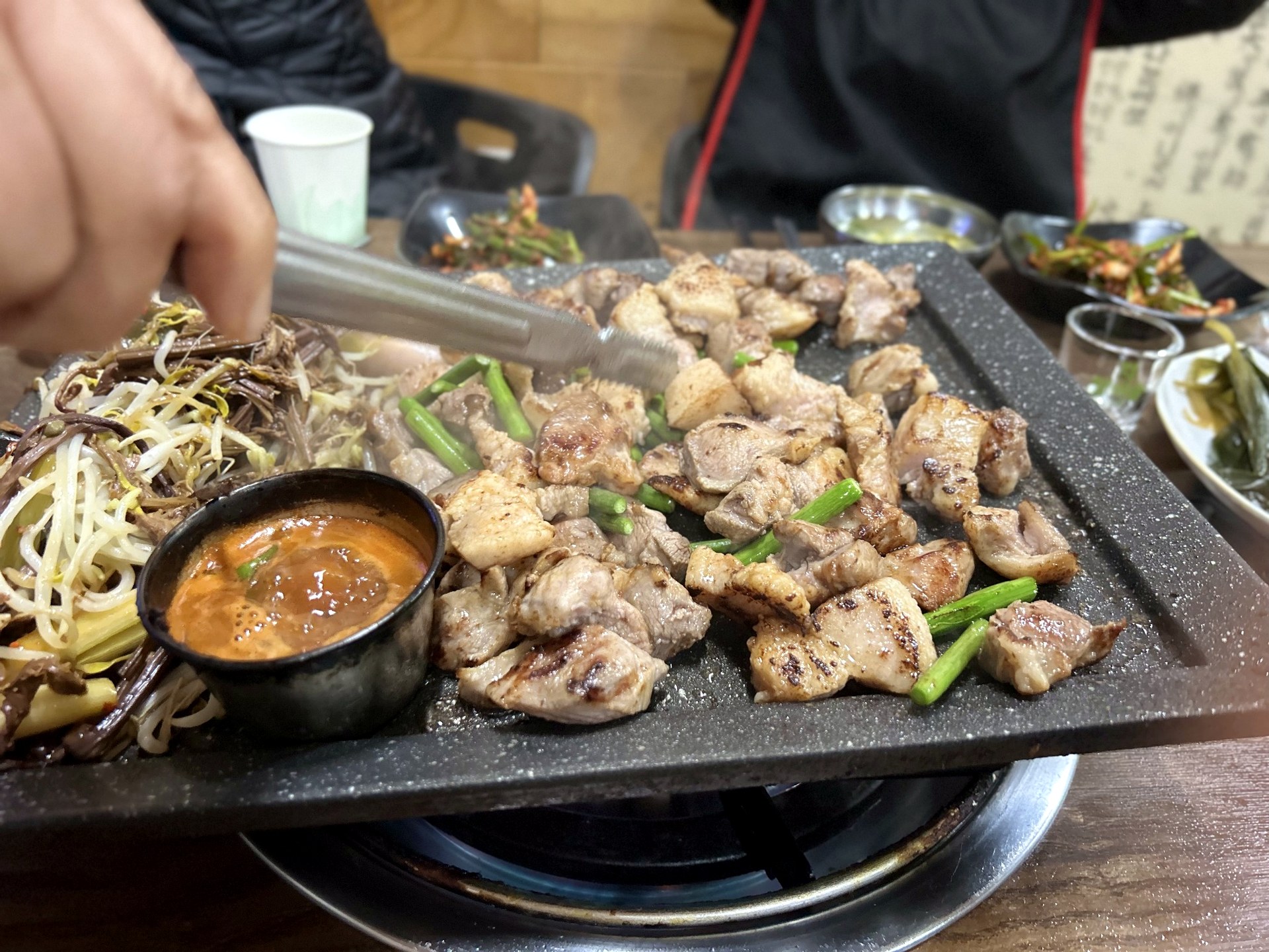 Jeju pork grilling with gosari bracken fern on a tabletop grill