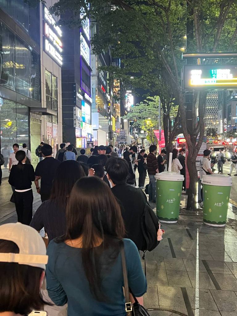 Passengers waiting at a central bus stop in Seoul at night