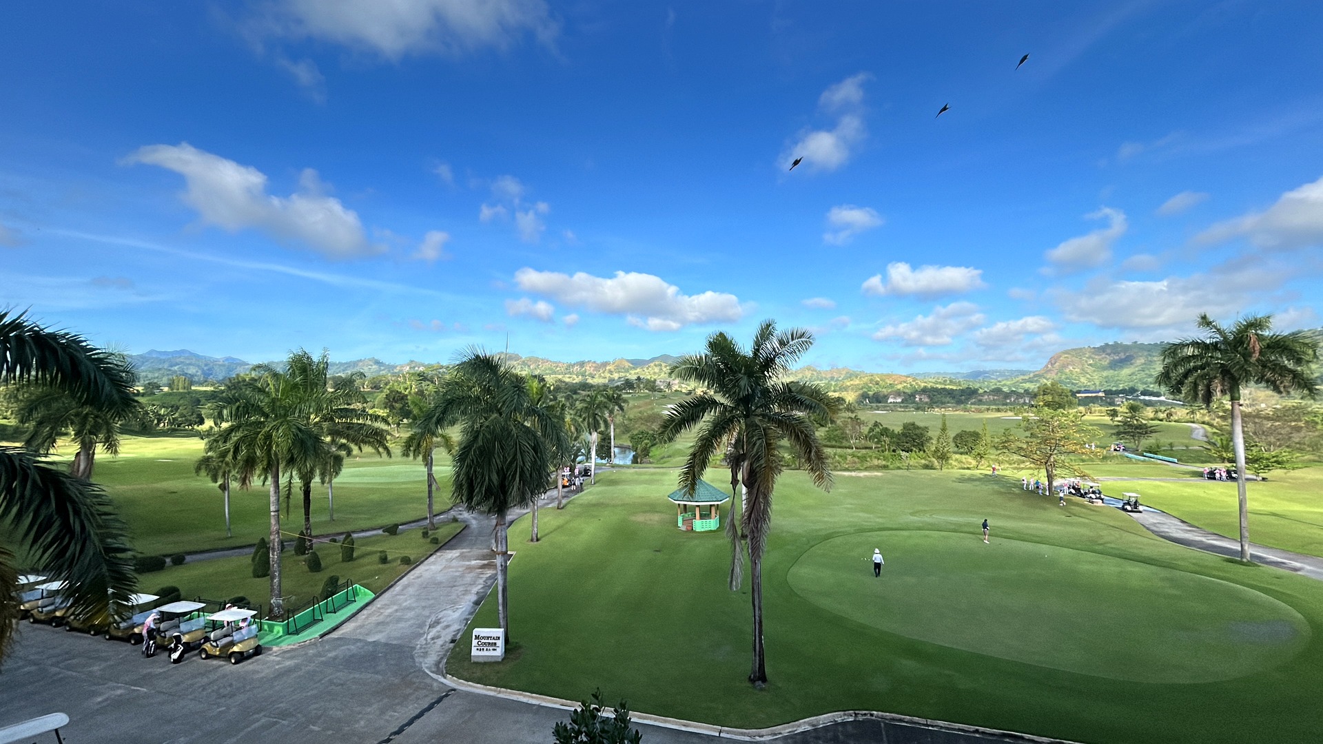 Tropical golf course in the Philippines with palm trees, fairway and golf carts
